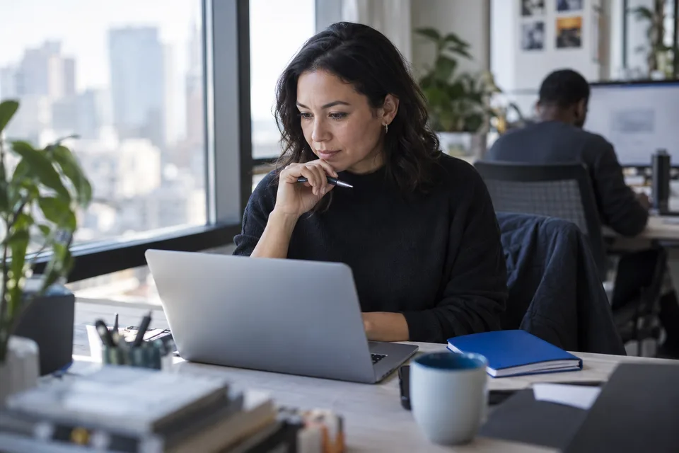 A marketing lead reading an AI answer on a laptop at a window desk