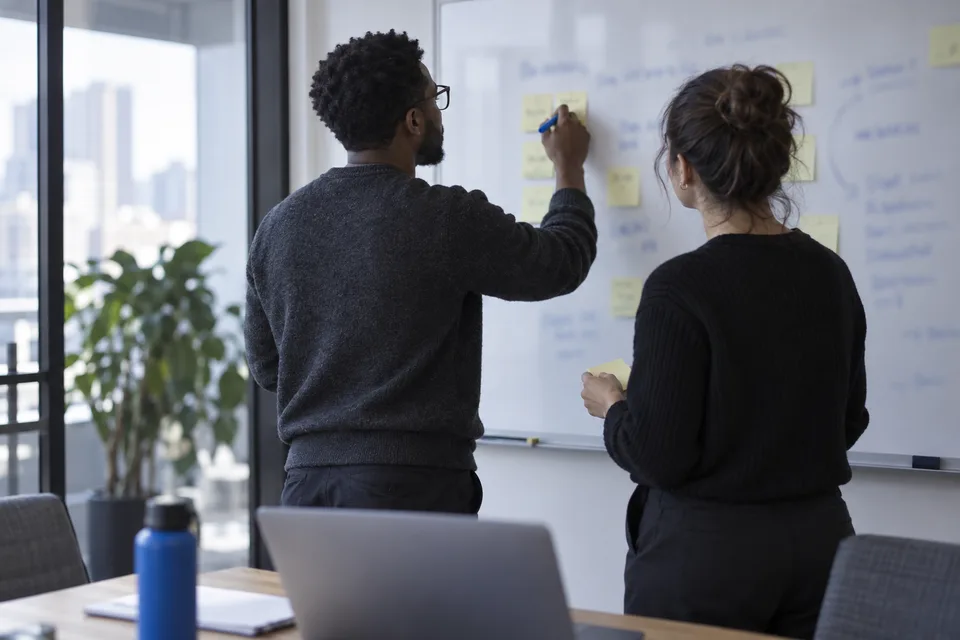 Two colleagues listing buyer questions on a whiteboard